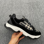 Black lace-up sneakers with beige check detail, chunky white sole, and ridged tread