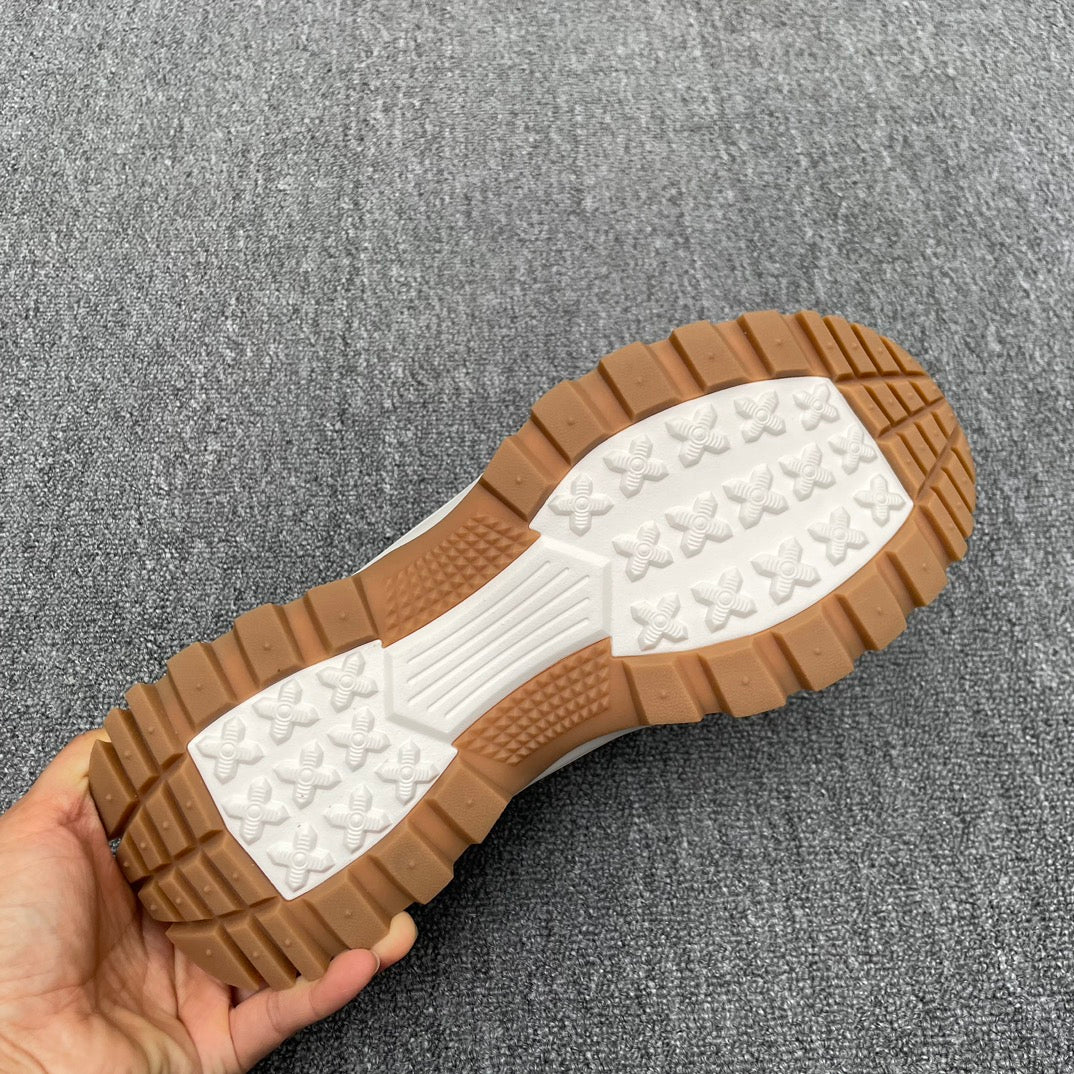 Outsole view of tan-and-white sneakers with patterned tread and rubber grip