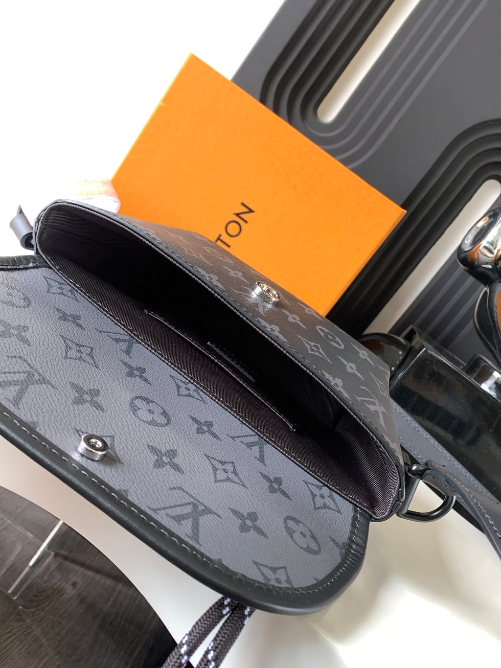 Louis Vuitton bag side view with gray monogram canvas, stitched trim, and strap