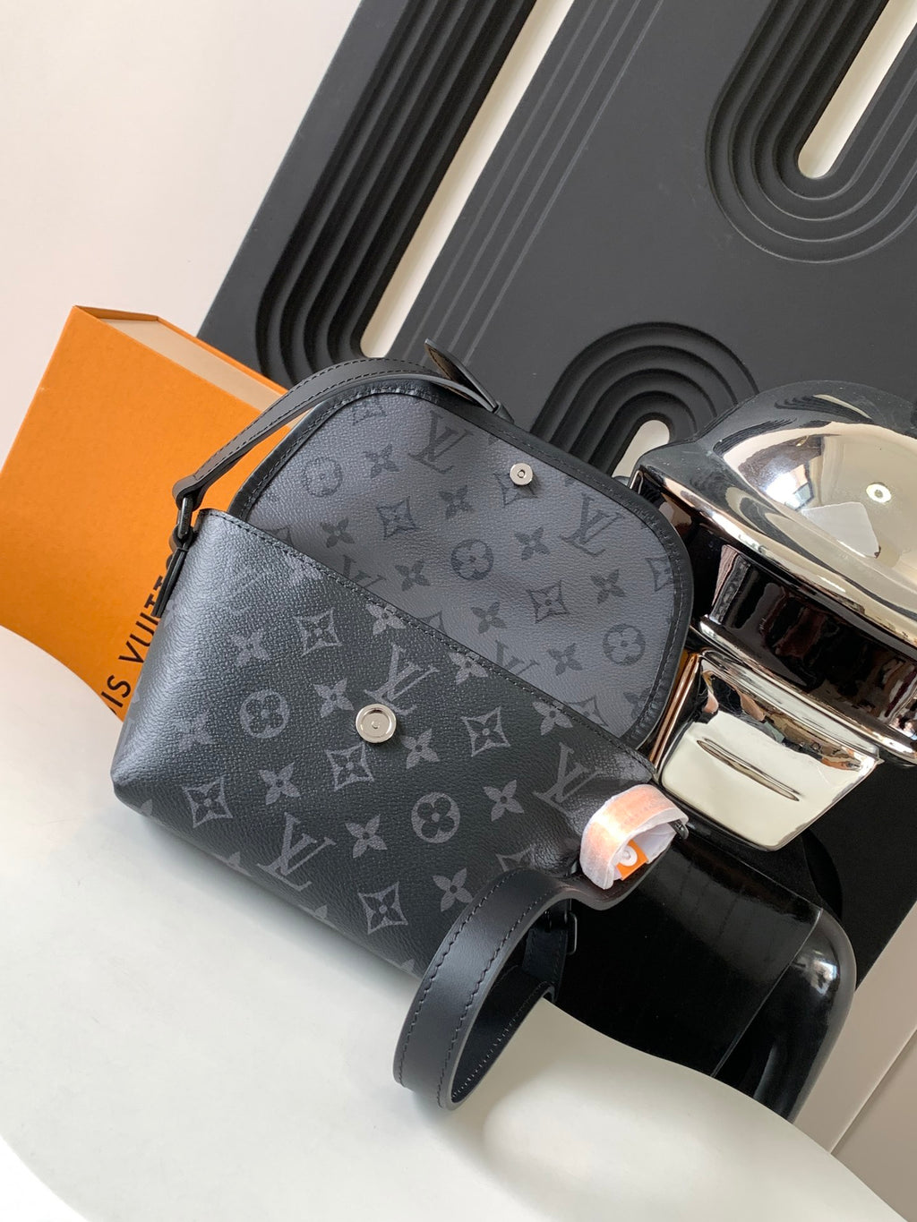 Louis Vuitton bag with gray monogram print, front zipper pocket, and snap button