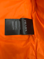 Prada care label on orange lining inside a long puffer jacket.