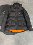 Black long puffer jacket with hood, button front, and orange inner lining.