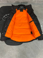 Black long puffer jacket with hood and orange inner lining panels.