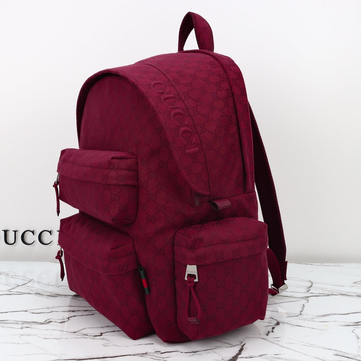 Gucci burgundy GG-pattern backpack with front utility pockets and top handle