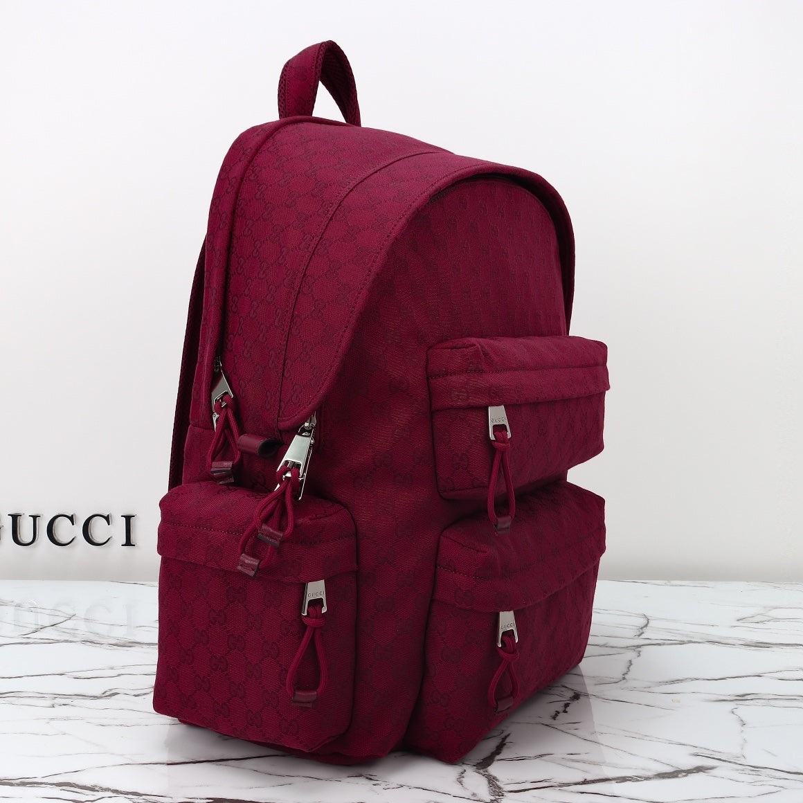 Gucci burgundy GG-pattern backpack with two front pockets and top handle