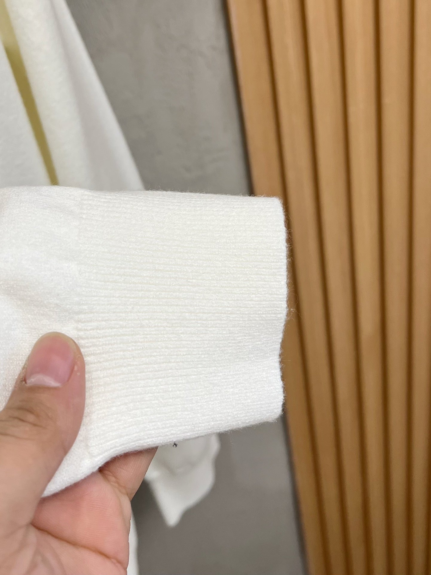 White sweatshirt cuff and ribbed hem held in hand