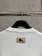 White sweatshirt back with small gold logo patch near the collar