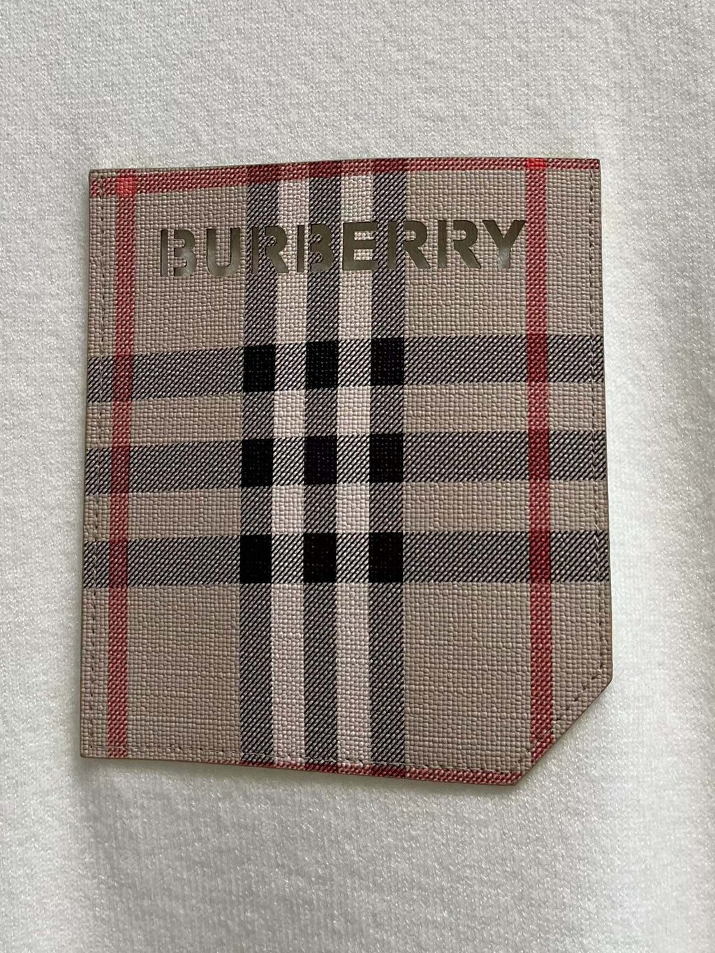 White sweatshirt chest pocket patch with red, black, and beige plaid logo