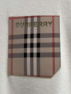 White sweatshirt chest pocket patch with red, black, and beige plaid logo