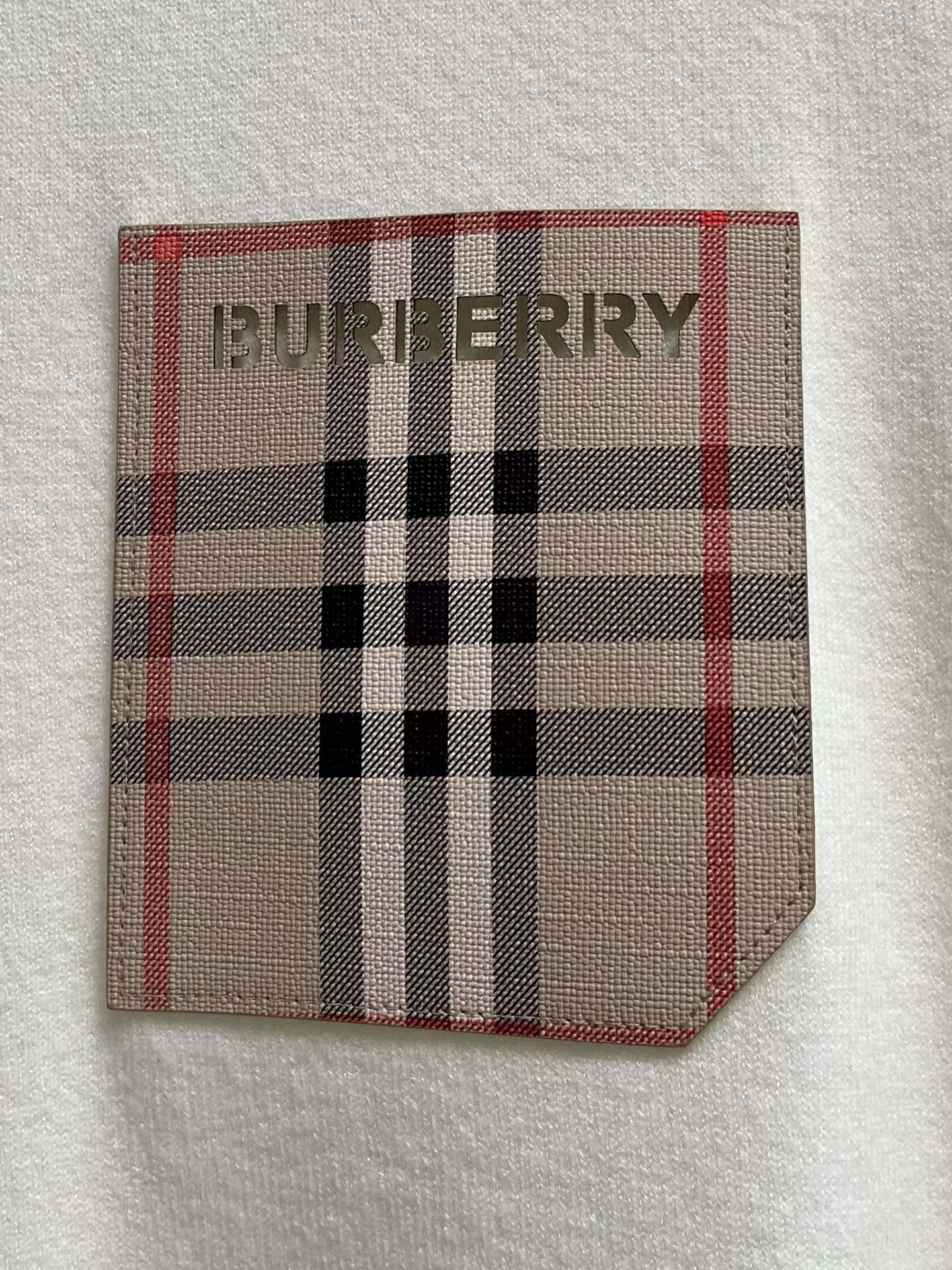 White sweatshirt chest pocket patch with red, black, and beige plaid logo