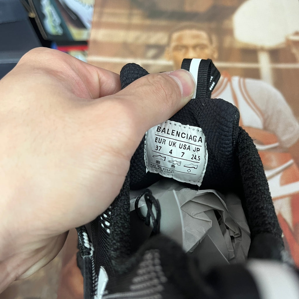 Black sneaker interior with size label tag and white stripe strap detail