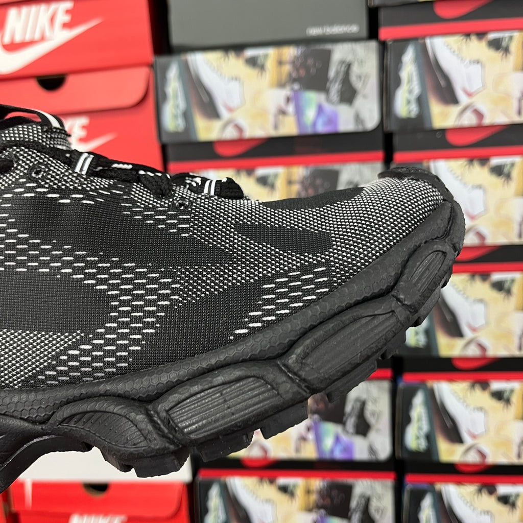Black knit sneaker side view with white stripe pattern and chunky sole