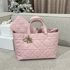 Pink quilted tote bag with top handles and gold-tone logo charm, open front view