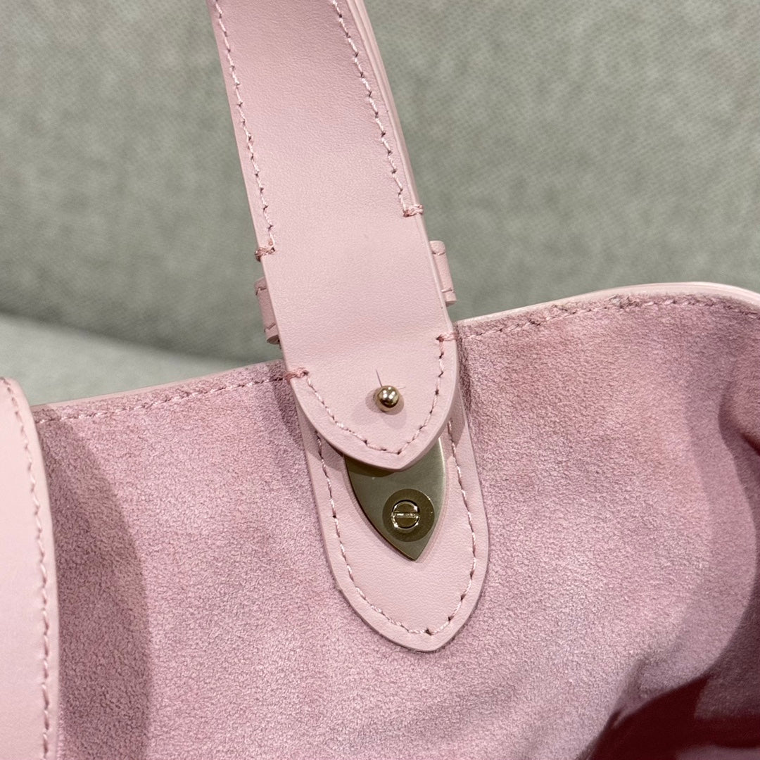 Pink bag strap attachment with stitched loop and small gold-tone button detail