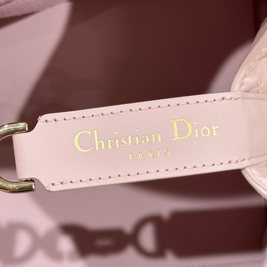 Pink leather tag on bag strap reading “Christian Dior PARIS” with gold-tone hardware