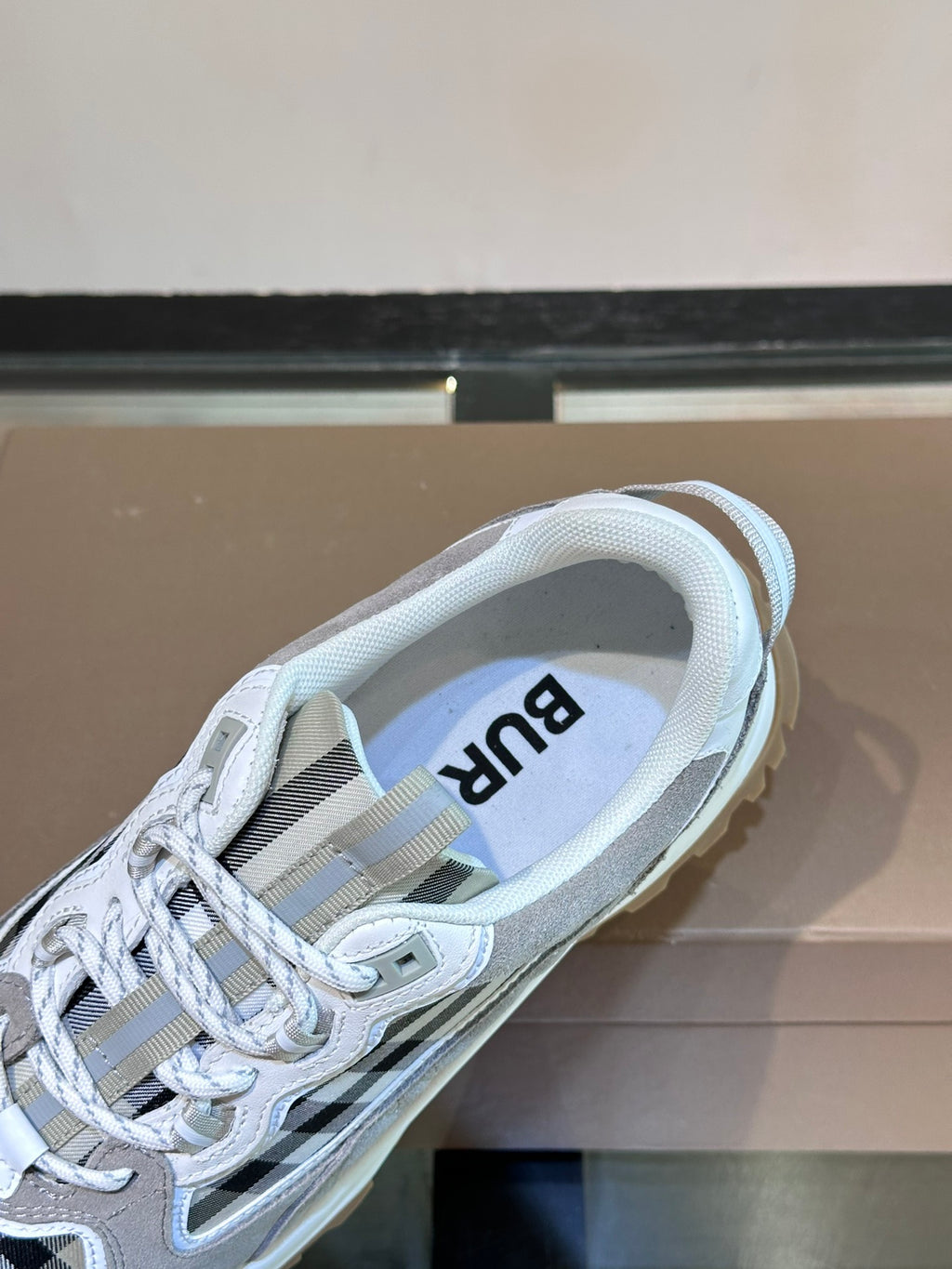 Inside view of Burberry lace-up sneaker with grey laces and blue logo text on insole