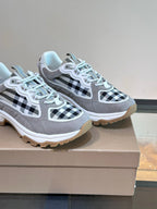 Two Burberry grey lace-up sneakers on box, featuring black-and-white check overlays