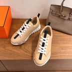 Beige leather low-top sneakers with white laces, black stripe detail, thick rubber sole