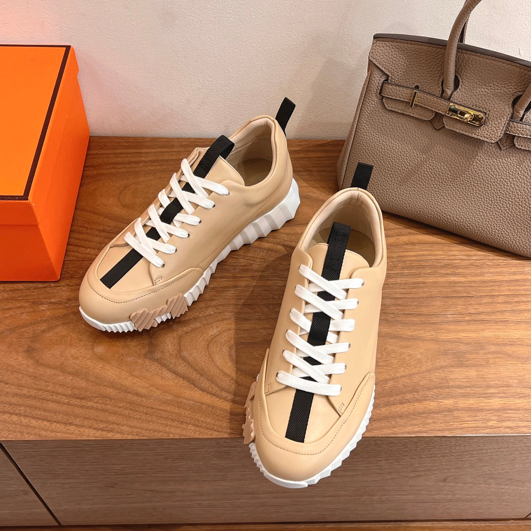 Beige leather low-top sneakers with white laces, black stripe detail, thick rubber sole