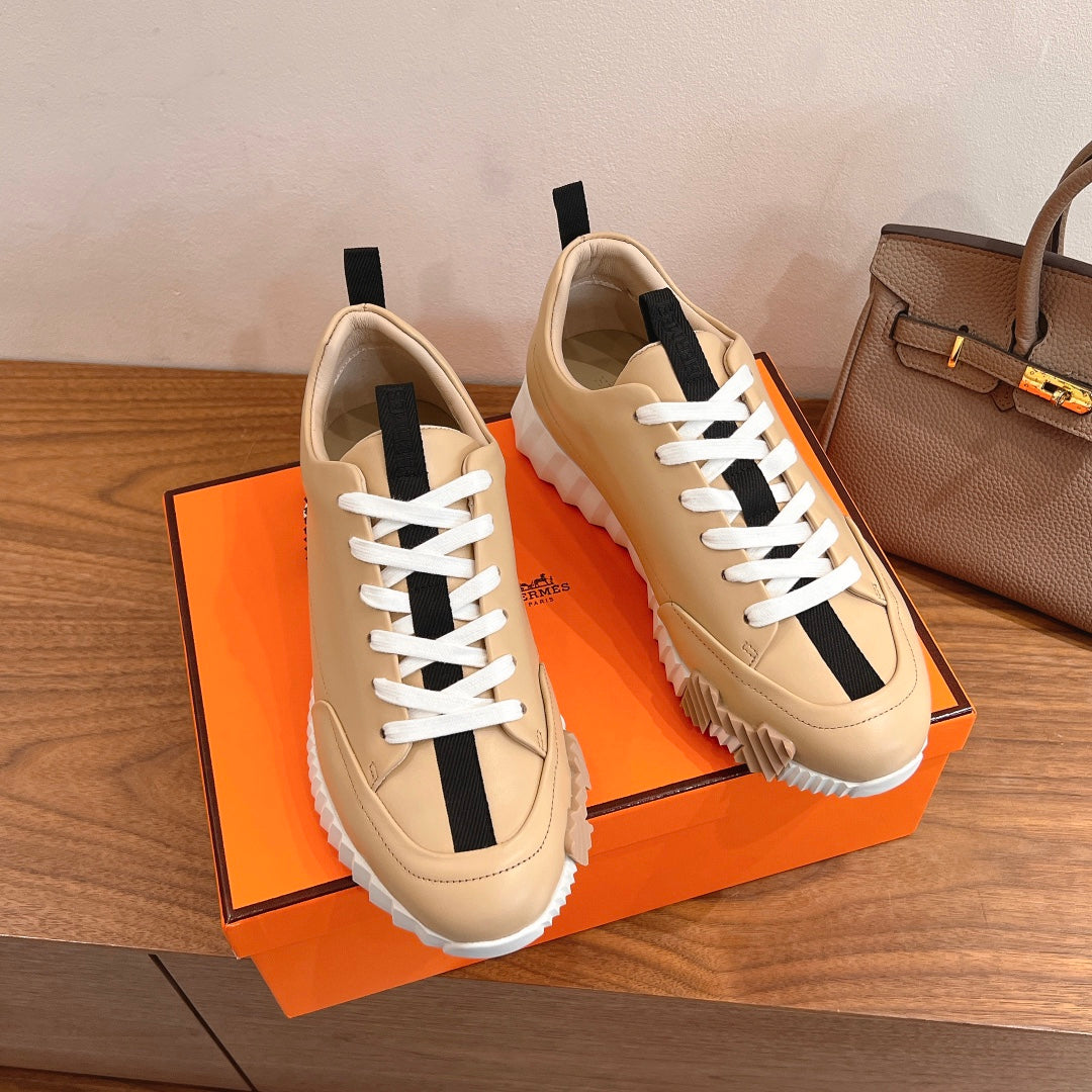Beige leather sneakers with white laces and black heel-tab accents, chunky tread sole