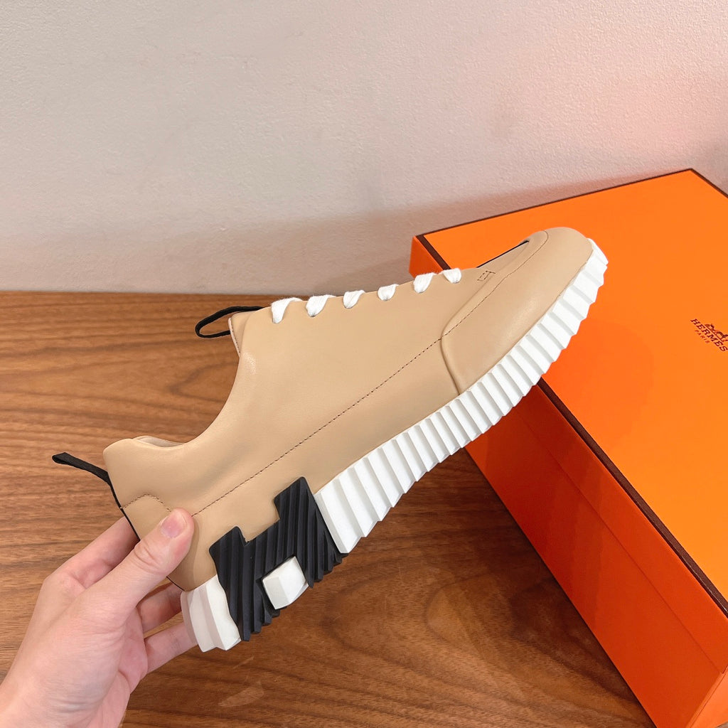 Beige leather sneaker with white laces, black side panel, striped rubber sole
