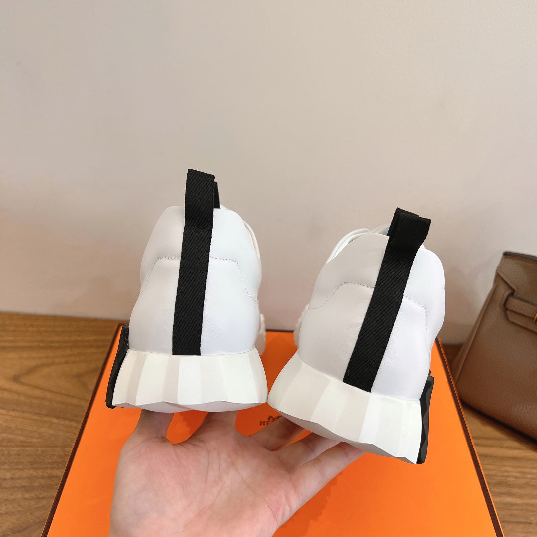 Pair of white sneakers from back with black heel tabs, Hermes unisex.