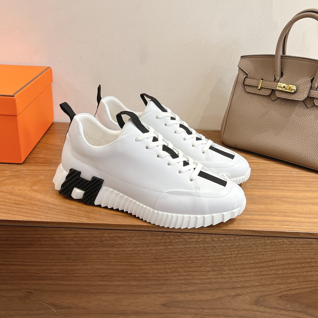 White sporty sneakers with black side panel detail, lace-up front, Hermes unisex.