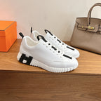 White sporty sneakers with black side panel detail, lace-up front, Hermes unisex.