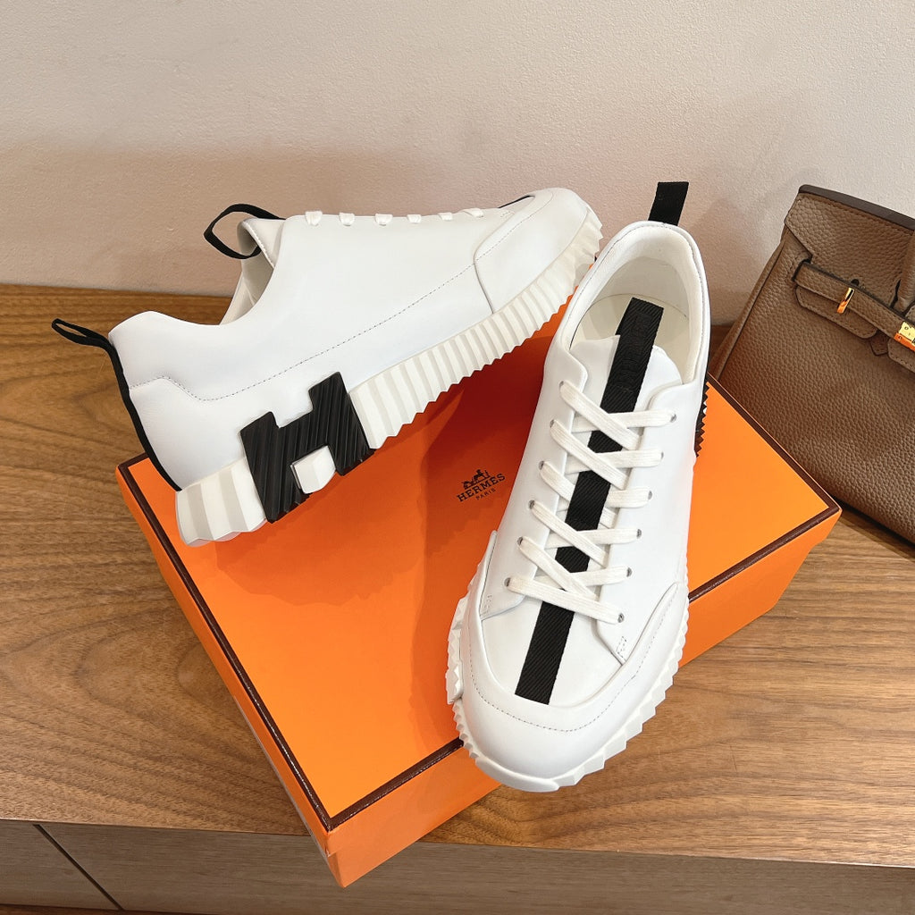 White lace-up sneakers with black heel strap detail and thick rubber sole, Hermes.