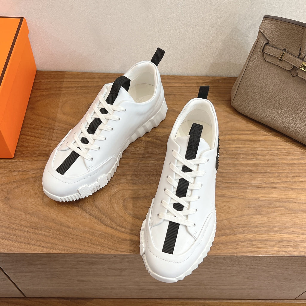 Pair of white lace-up sneakers with black side stripe and chunky rubber sole, Hermes.