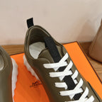 Olive leather sneaker close-up with white laces and black strap detail