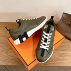 Olive leather sneakers with white laces and black sock-like detail, chunky white sole