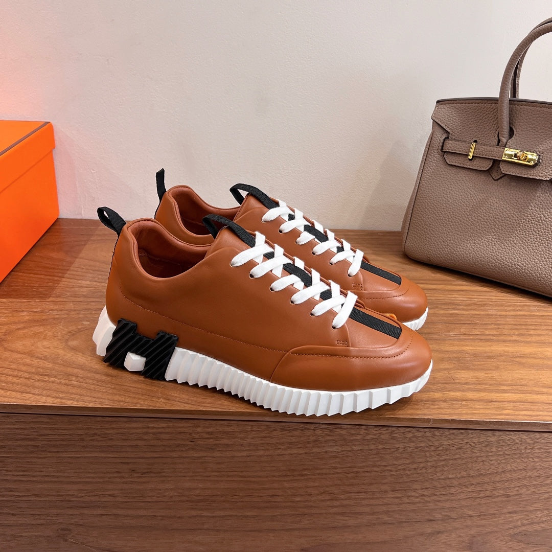 Tan leather sneakers with white laces, black side stripes, thick white sole