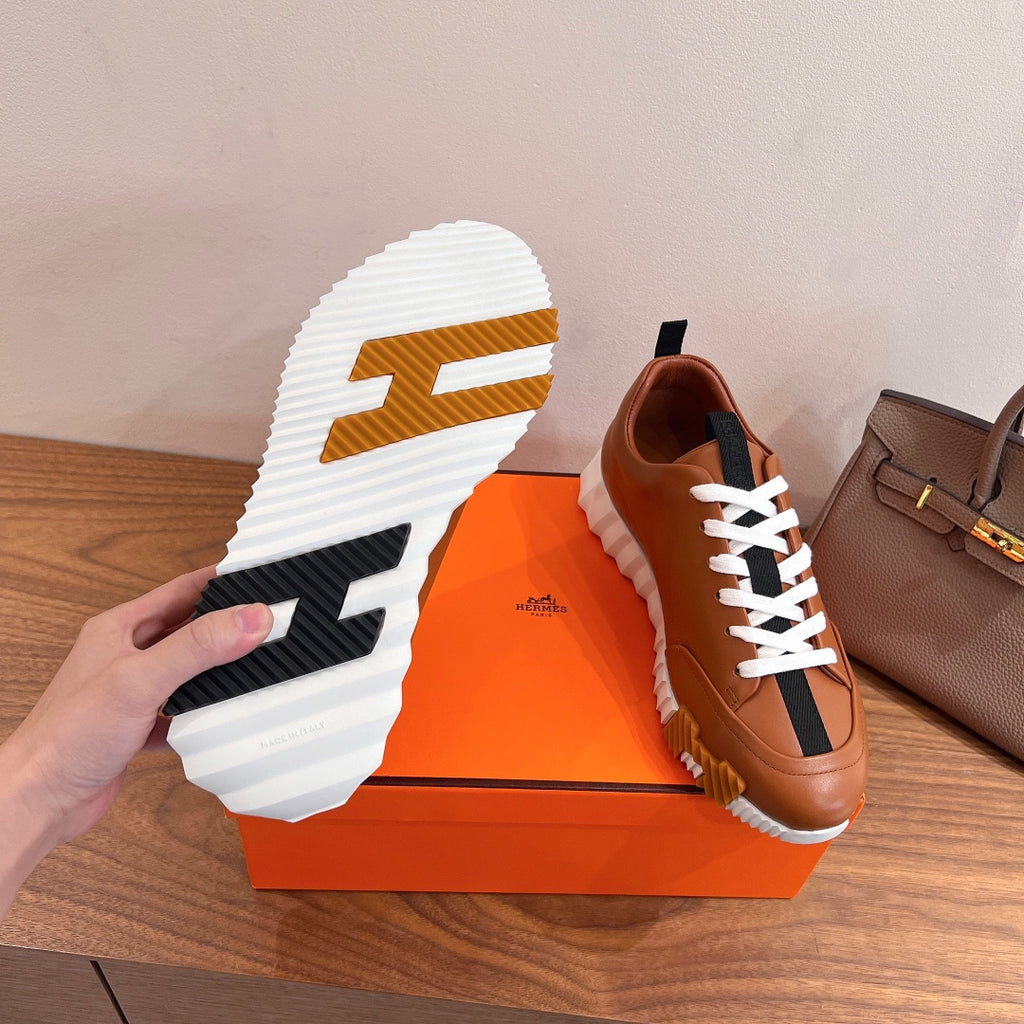 Sneaker outsole view with brown tread detail and white rubber sole on box