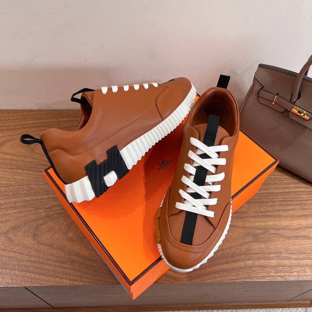 Tan leather lace-up sneakers with white laces and black side stripe on box