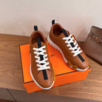 Tan leather lace-up sneakers with black side stripe displayed on orange box