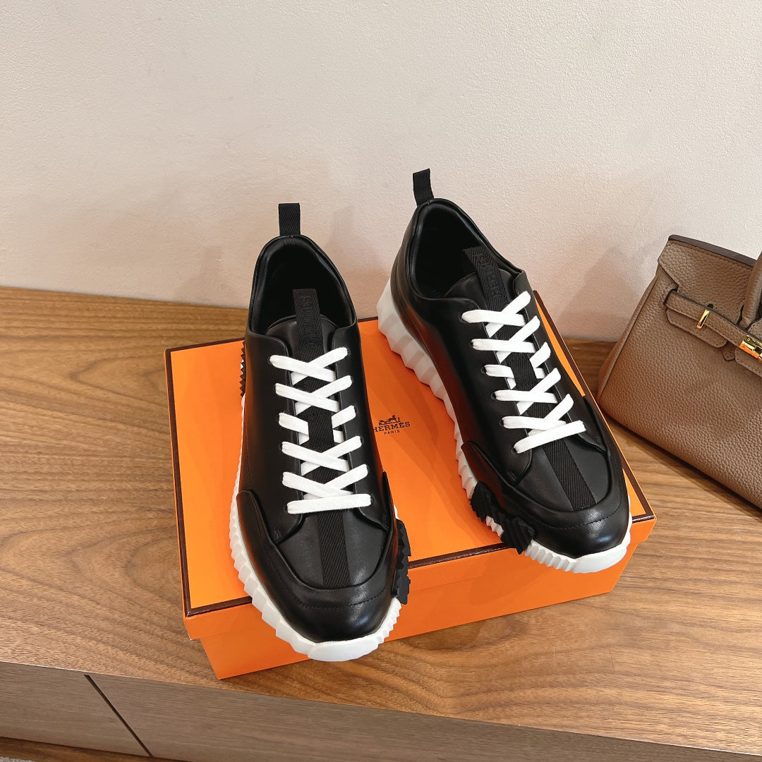 Pair of black leather sneakers with white lace-up ties and thick white sole
