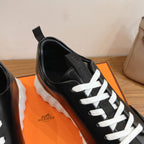 Black leather sneaker with white laces and Hermes logo on tongue