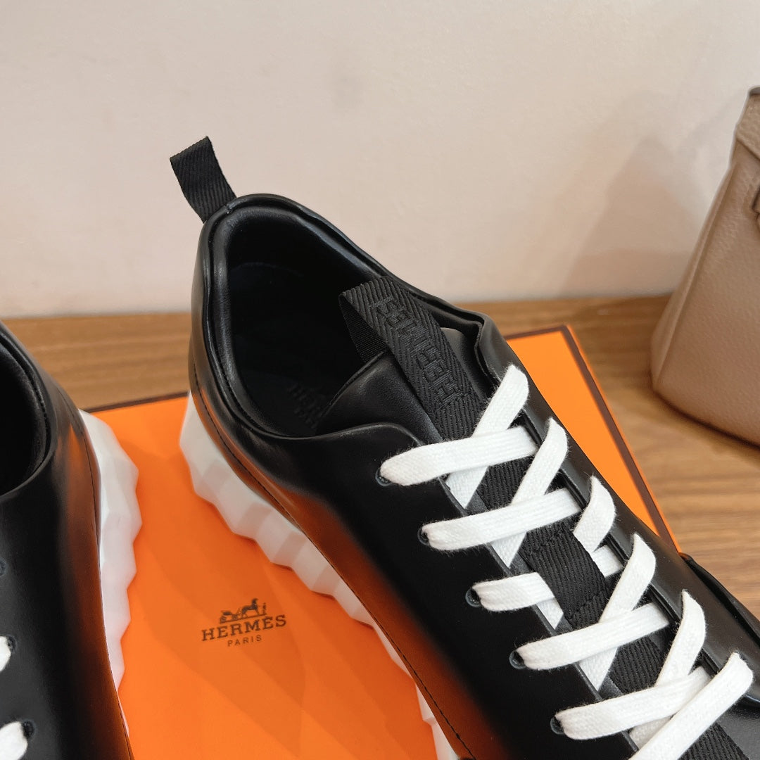 Black leather sneaker with white laces and Hermes logo on tongue