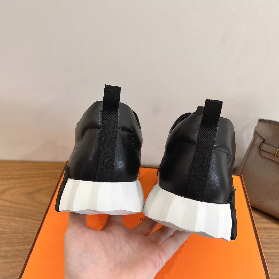 Black sneakers from the back with elastic pull tabs and white outsole