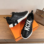 Black sneakers with white laces, chunky sole, and elastic side pull tabs