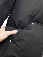Black puffer jacket side close-up with snap button pocket and quilted paneling