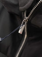 Black puffer jacket zipper close-up with metal zipper pull and logo tag