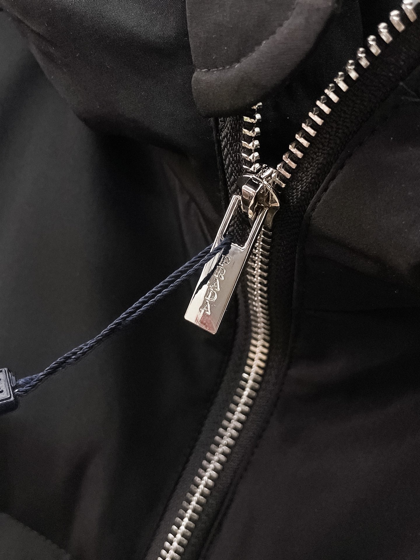 Black puffer jacket zipper close-up with metal zipper pull and logo tag