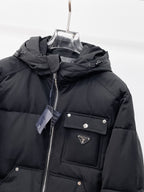 Black hooded puffer jacket front close-up with zipper, logo patch, and flap chest pocket
