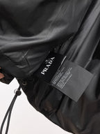 Long black coat with drawstring waist and Prada branded hang tag