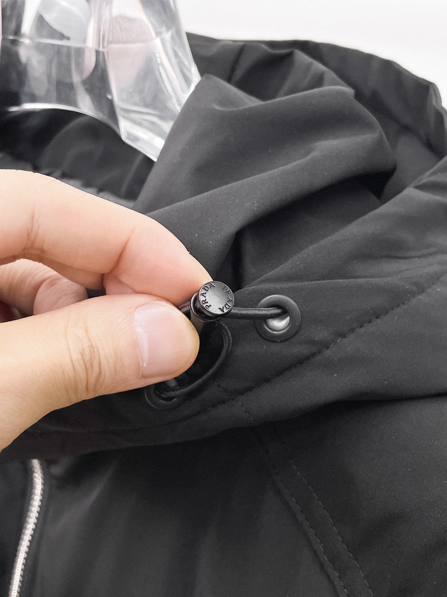 Black puffer jacket drawcord with round toggle stopper near the hood
