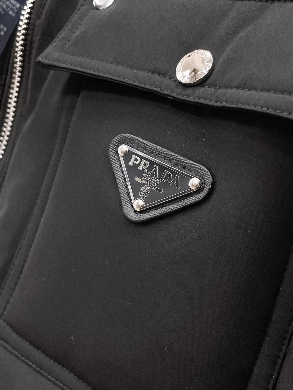 Black puffer jacket chest pocket close-up with triangular logo patch