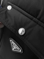 Black puffer jacket close-up of snap buttons and fabric logo patch on pocket