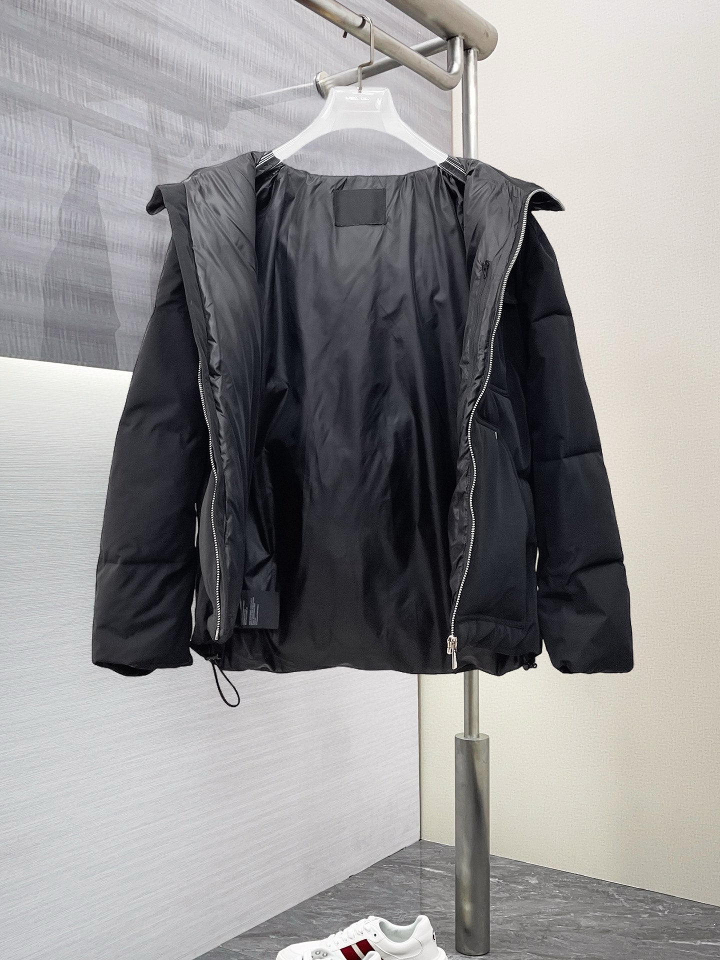 Black long puffer jacket with hood, front zipper, and visible inner paneling